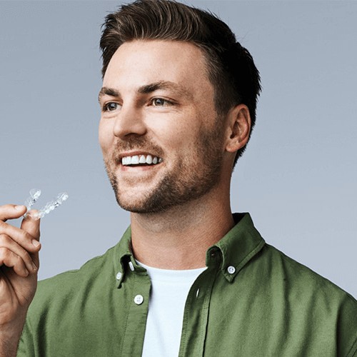 man holding clear aligners smiling